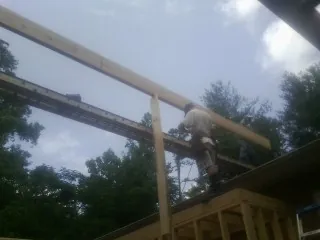 Carpenter setting a ridge beam over a new addition frame — Ice Dam Removal by Roofing Brothers in Saint Augustine