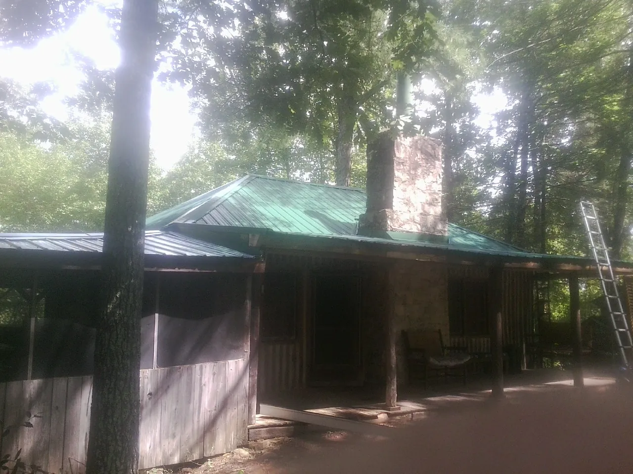 Green metal roof and stone chimney above a log cabin porch in Saint Augustine