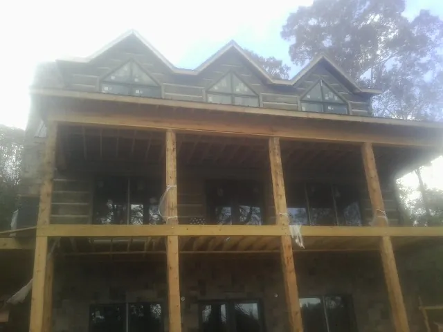 Dormers and porch framing on a large log home under construction — Roof Coating work by our crew in Saint Augustine
