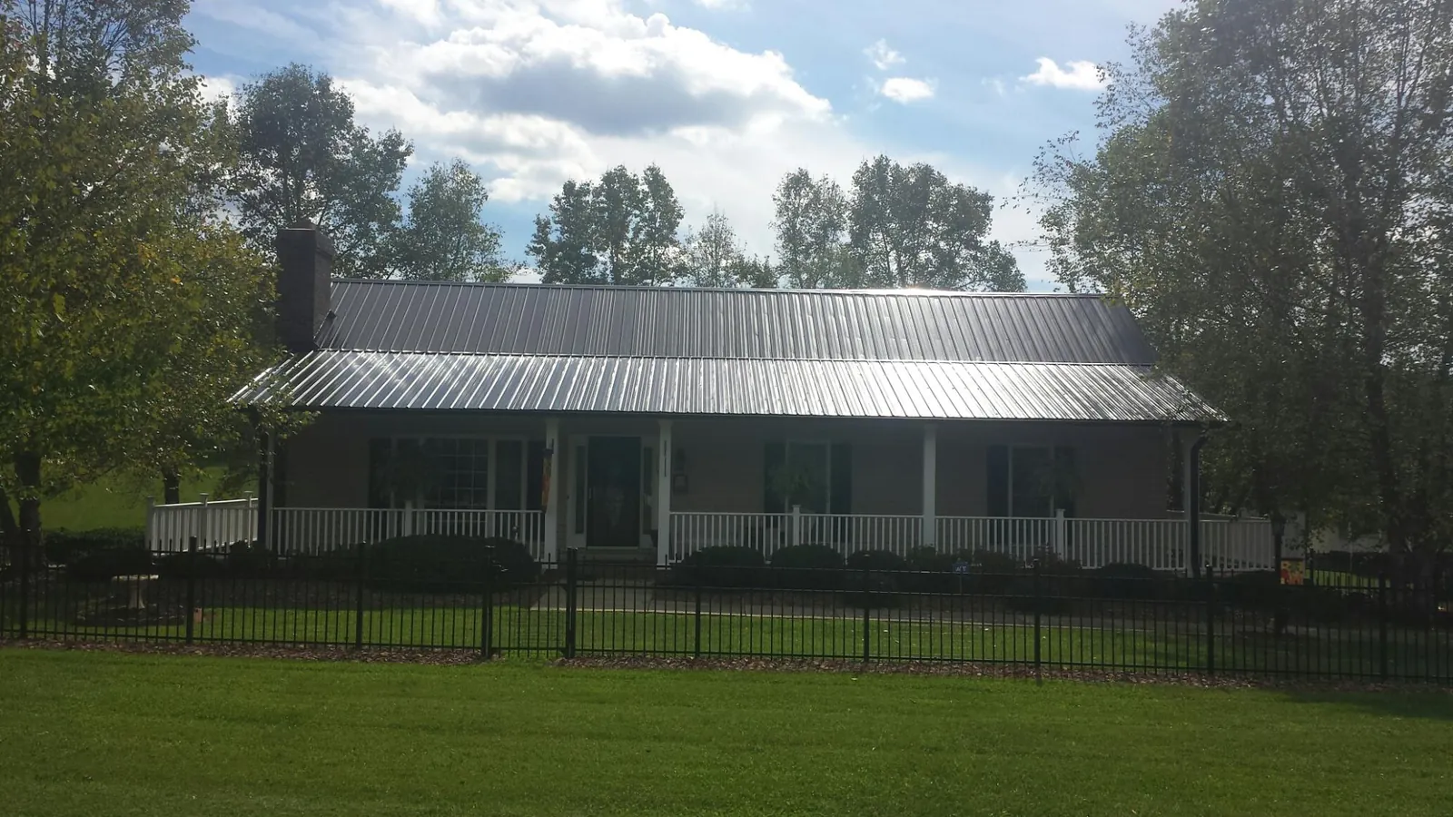 Gray metal roof on a brick ranch with a full width front porch — Gutter Guard Installation work by our crew in Saint Augustine